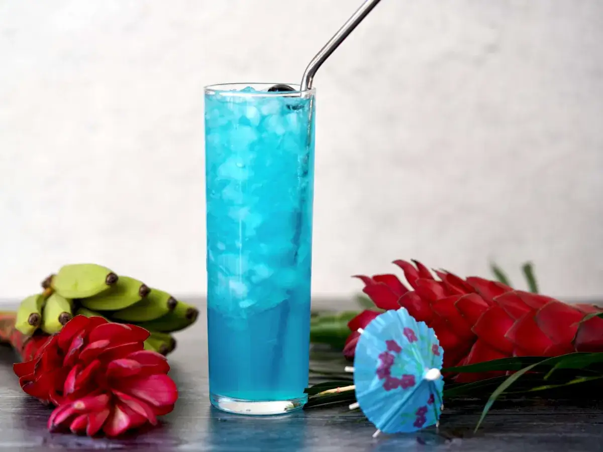 Błękitna laguna drink, orzeźwiający napój z lodem, ozdobiony tropikalnymi kwiatami i bananami.
