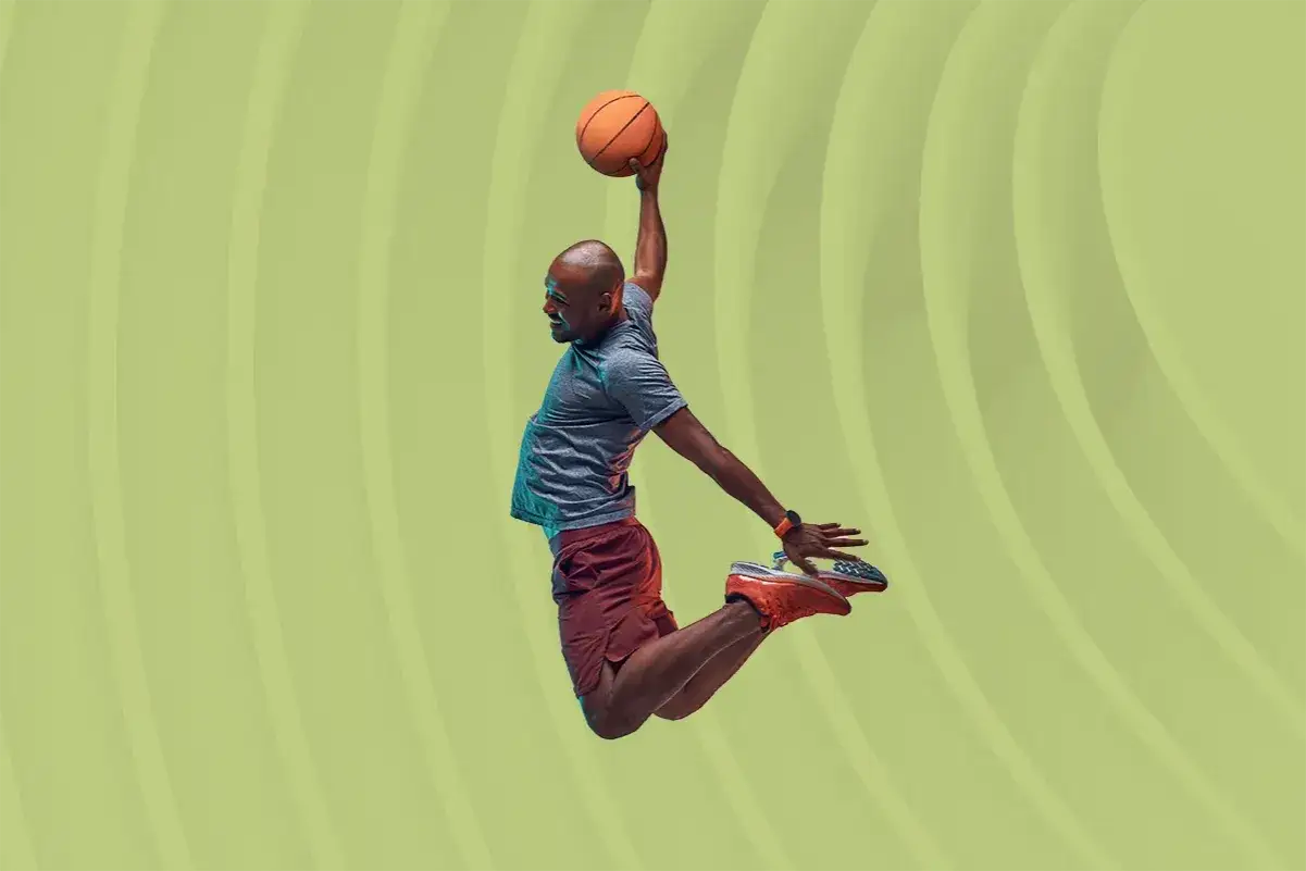 Mann springt mit Basketball in der Luft. Krafttraining und Basketball gehen Hand in Hand für diese athletische Leistung.