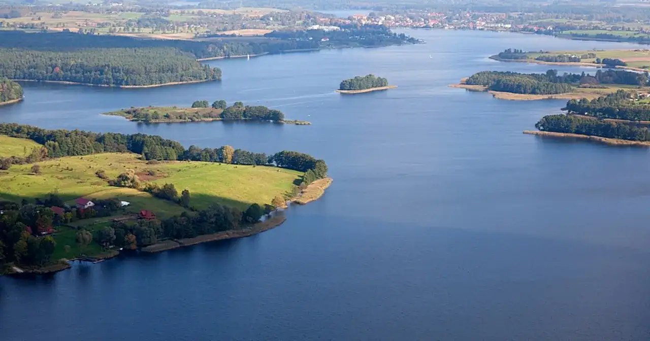 Malowniczy widok na najgłębsze jezioro na Mazurach, z wyspami, lasami i zielonymi polami.