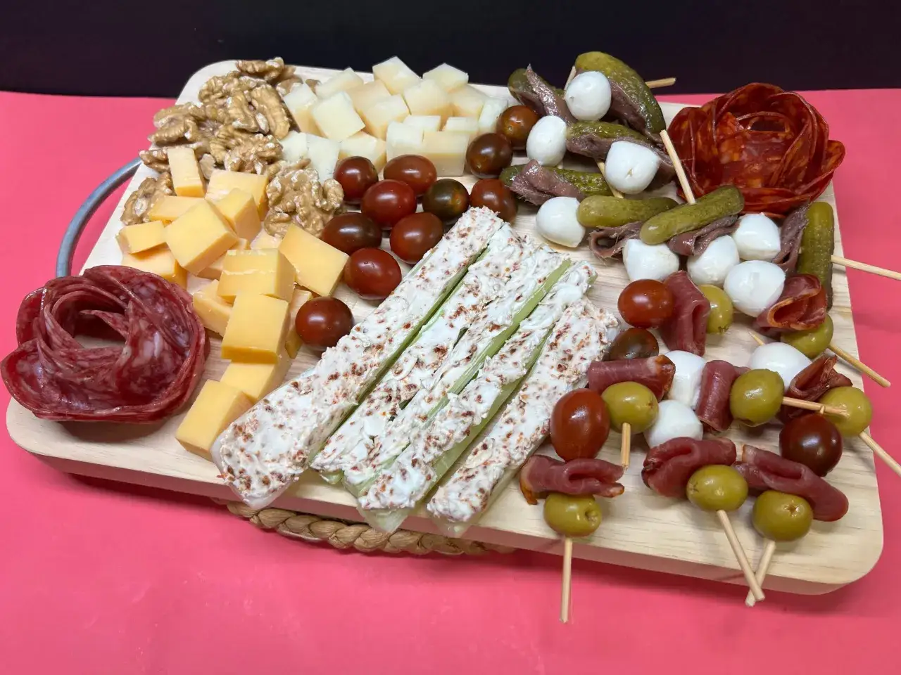 Tabla de pinchos y tapas originales: quesos, embutidos, aceitunas, tomates cherry, pepinillos, anchoas y apio con queso crema.