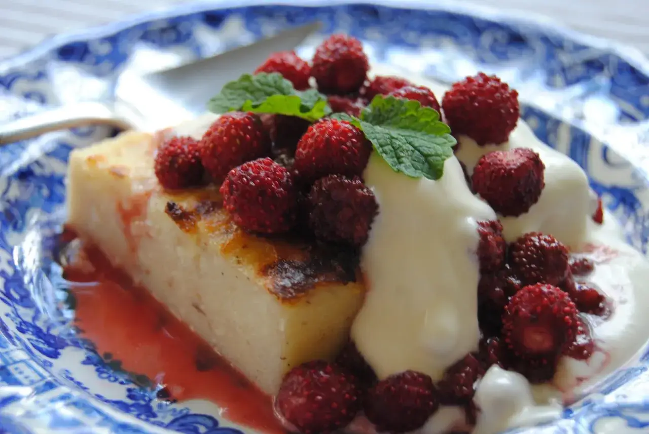 En bit krämig mannagrynspudding med färska skogsbär och mynta, serverad med grädde. Ett härligt recept på mannagrynspudding!