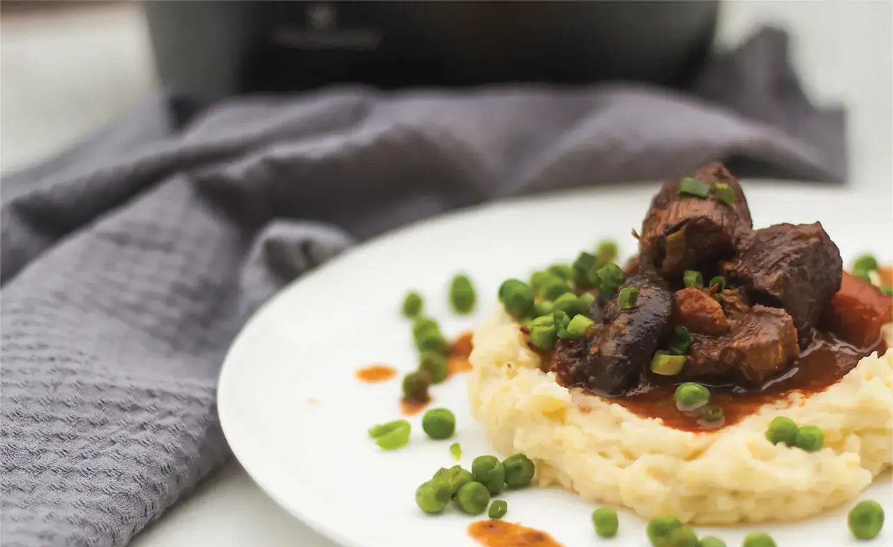 Pyszne wołowina po burgundzku na kremowym pur&eacute;e, posypana zielonym groszkiem i szczypiorkiem.