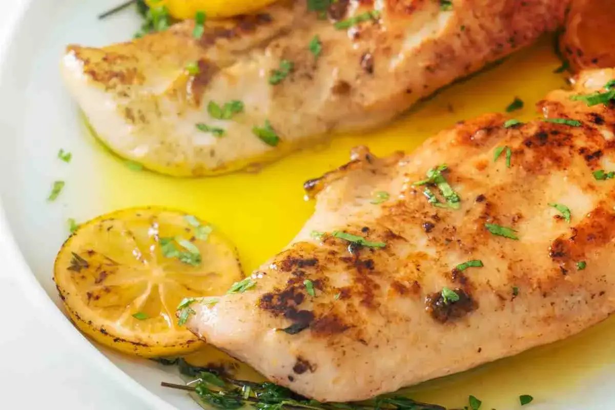 Deliziose scaloppine di pollo al limone, dorate e succulente, guarnite con fette di limone e prezzemolo fresco.