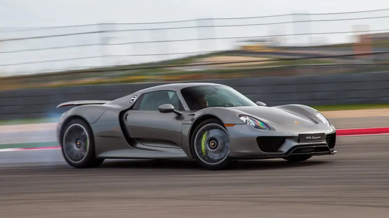 Grauer Porsche Hypercar 918 Spyder driftet auf der Rennstrecke, Reifen rauchen.