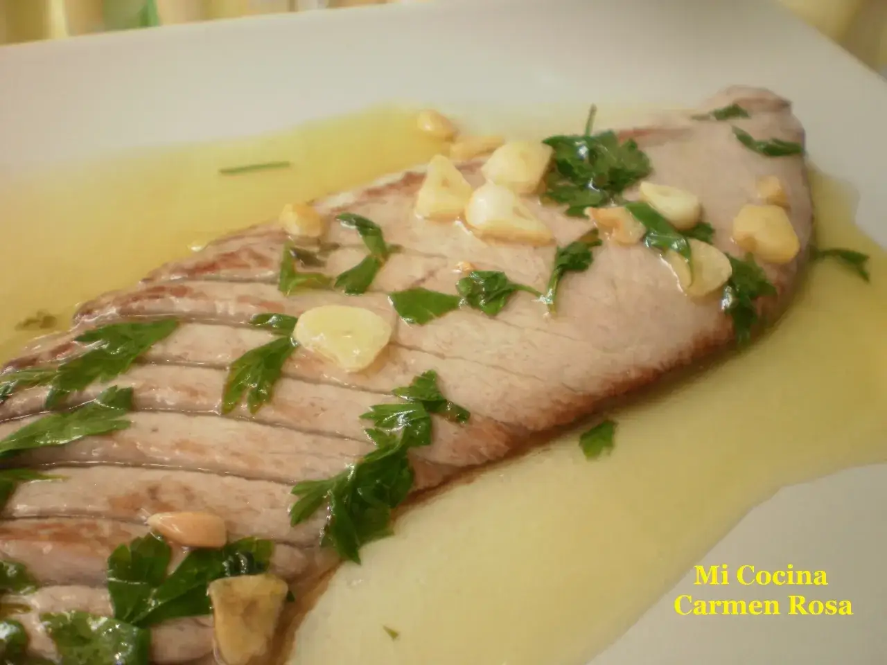 Deliciosa ventresca a la plancha con ajo laminado y perejil fresco, nadando en un sabroso aceite.