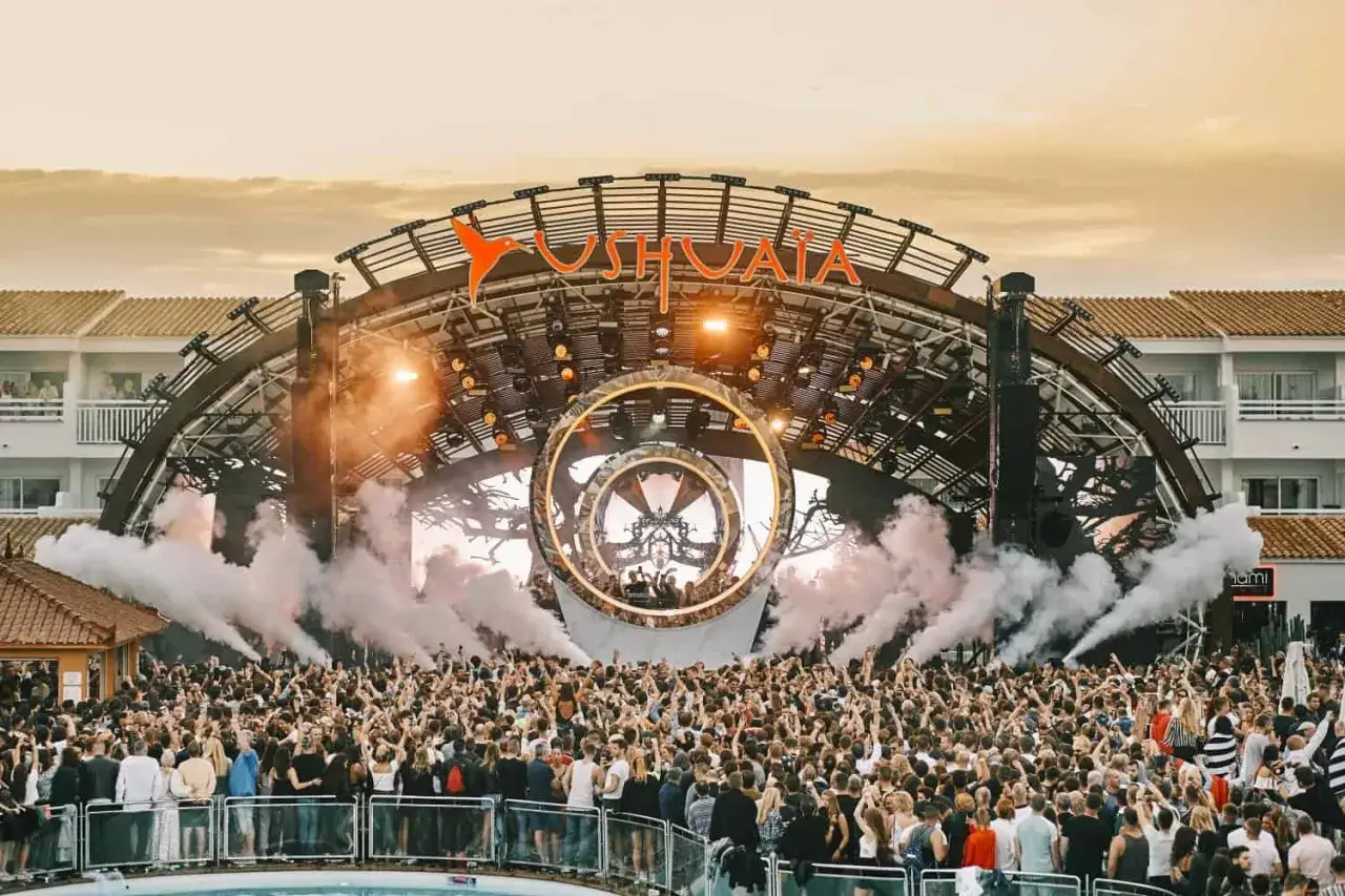 Festa all'aperto con folla scatenata e fumo scenico. L'iconico logo Ushuaïa annuncia l'apertura delle discoteche a Ibiza.