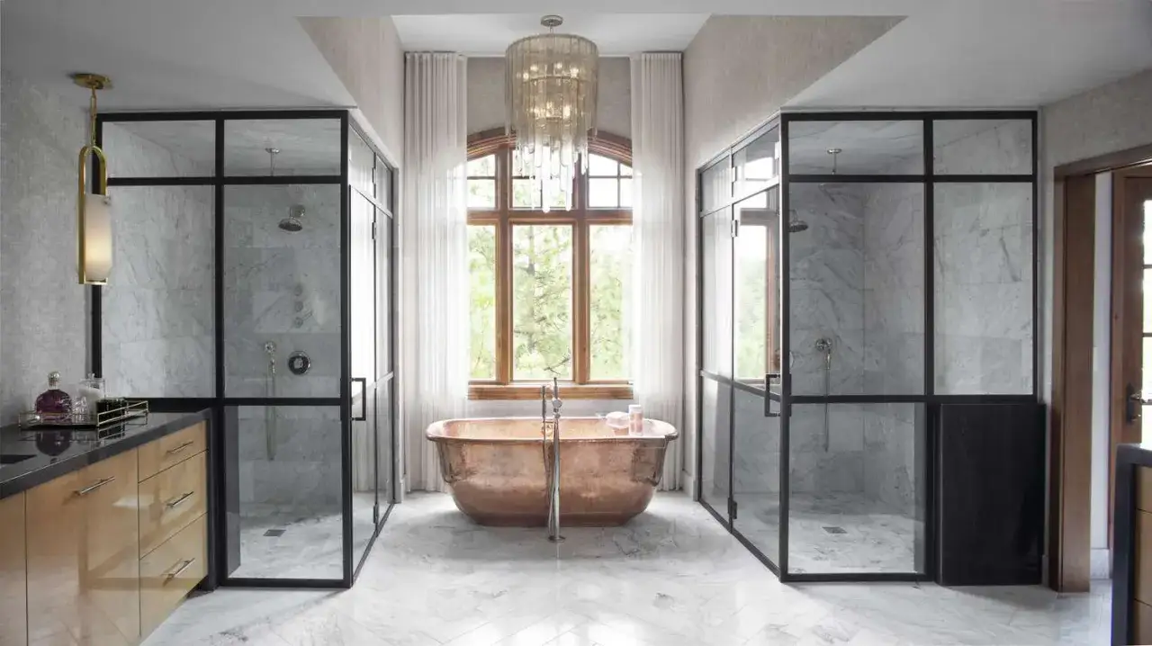Salle de bain luxueuse avec deux cabines de douche vitrées, une baignoire en cuivre et une grande fenêtre. La dimension cabine de douche est généreuse.