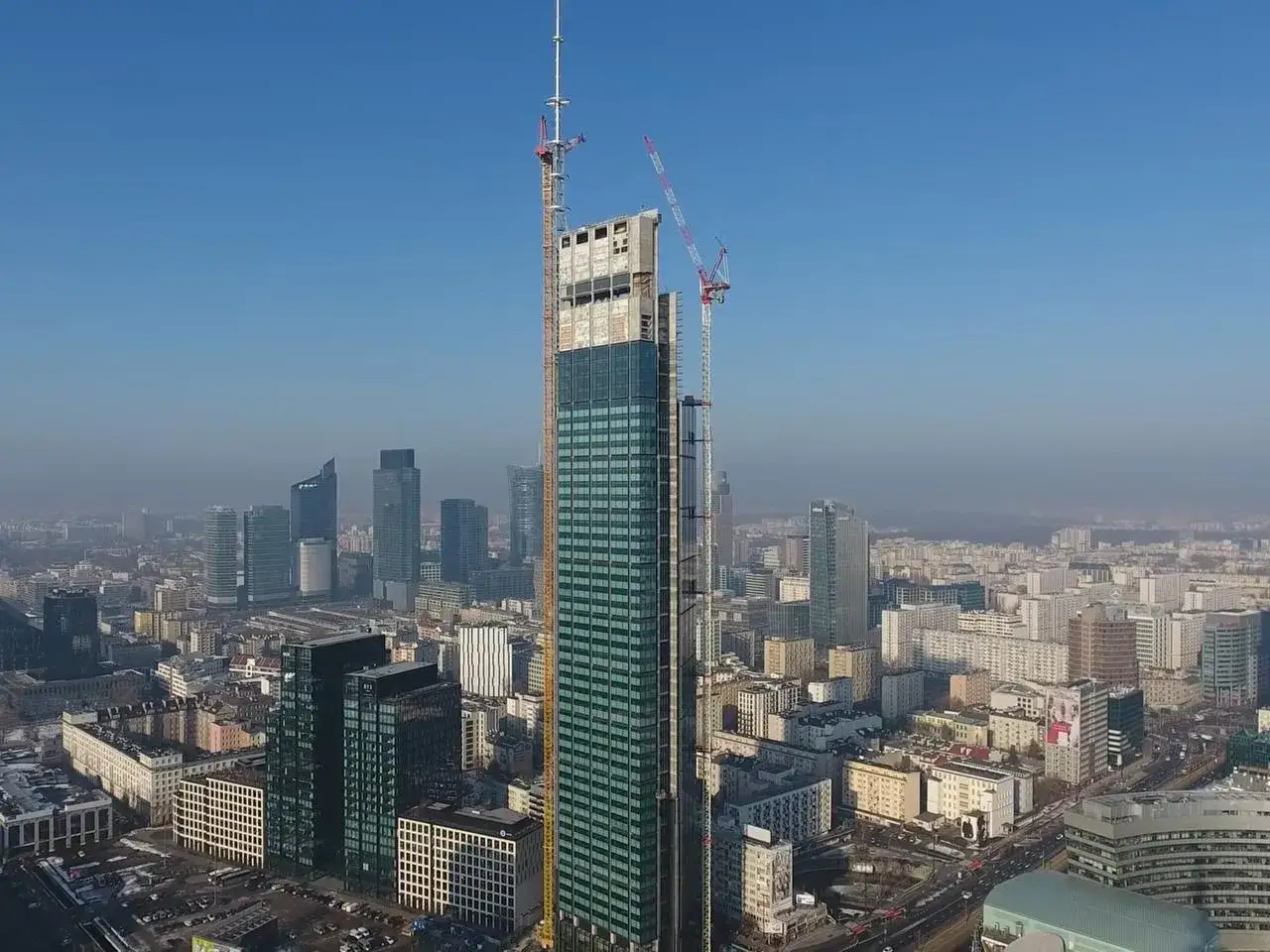 Varso Tower w budowie, z dźwigami na szczycie, góruje nad panoramą Warszawy. To już wkrótce będzie najwyższy budynek w Polsce, a jego wysokość to 300 metrów.