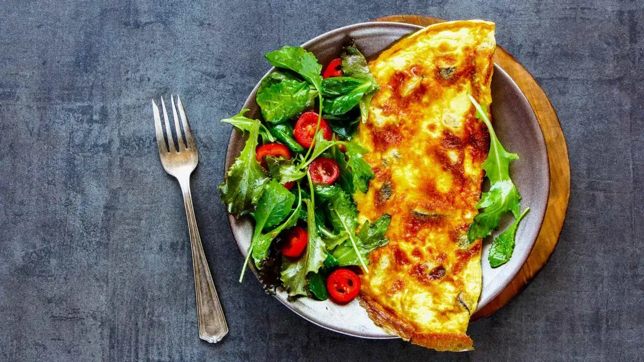 Frittata con pecorino dorata e soffice, servita con un'insalata fresca di rucola e pomodorini. Un piatto semplice e gustoso.