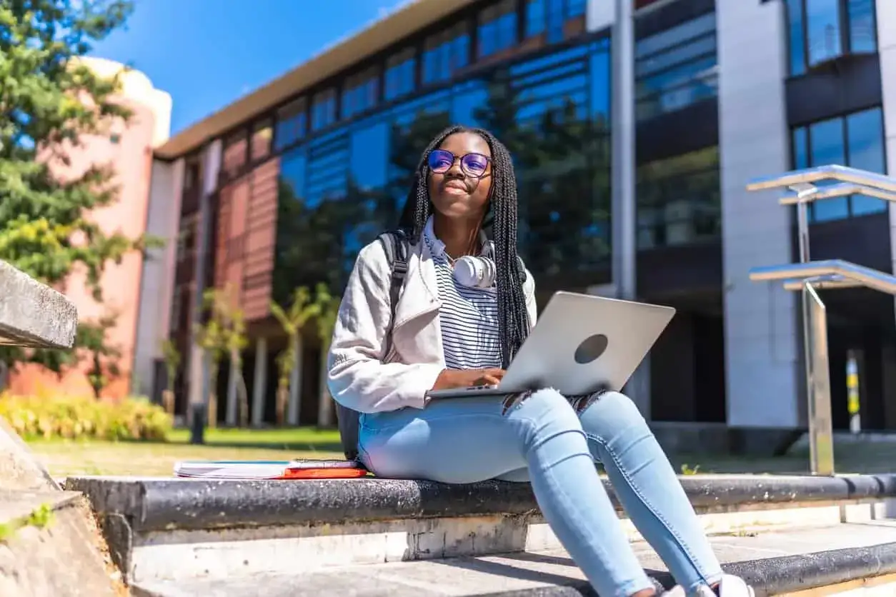 Joven española con portátil en campus universitario de EE.UU., soñando con estudiar en estados unidos siendo español.