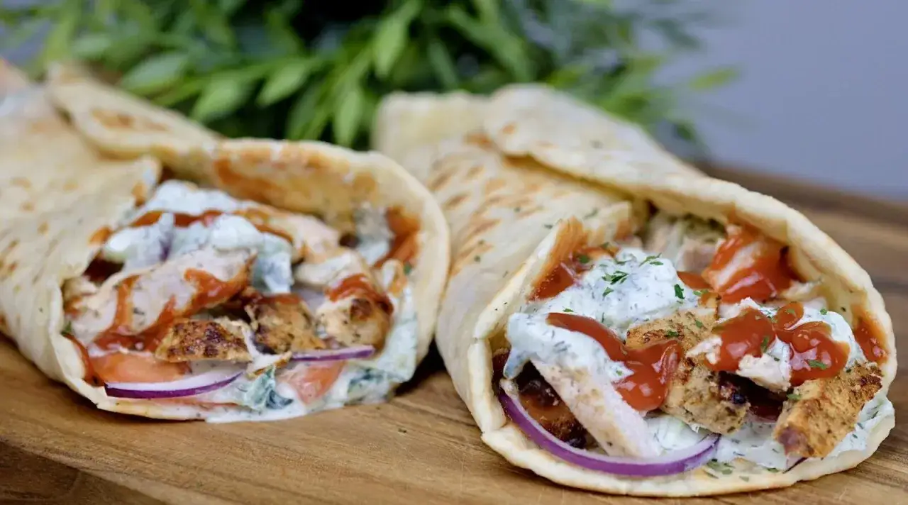 Dwa pyszne wrapy z kurczakiem gyros, polane sosem jogurtowym i keczupem, z dodatkiem świeżych warzyw.