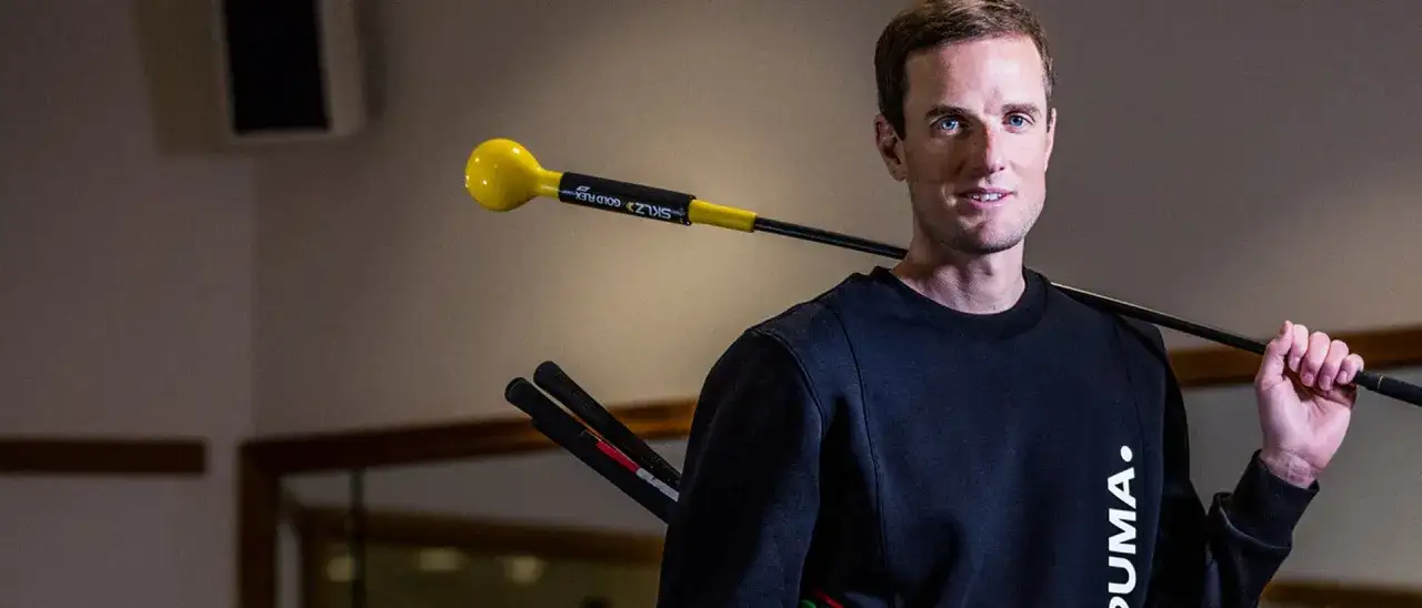 Man med golfsvingstränare över axeln, redo för en perfekt golfsving.
