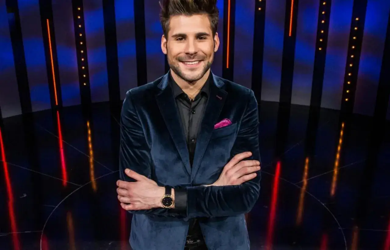 Uśmiechnięty Jan Pirowski, w aksamitnej marynarce i z różową poszetką, prezentuje się jak partner na scenie.