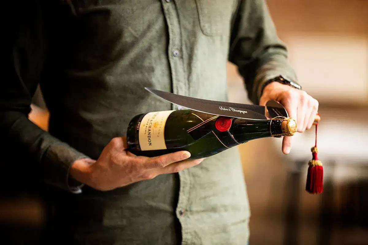 Un homme s'apprête à sabler le champagne, une tradition d'origine militaire pour ouvrir la bouteille avec un sabre.