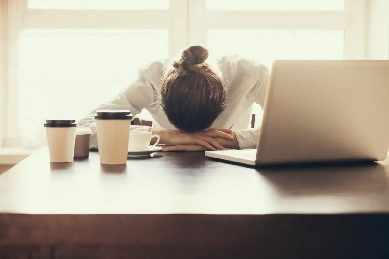 Stanca, con la testa appoggiata sulla scrivania e il caff&egrave; pronto, questa persona proprio non vuole tornare a lavoro.