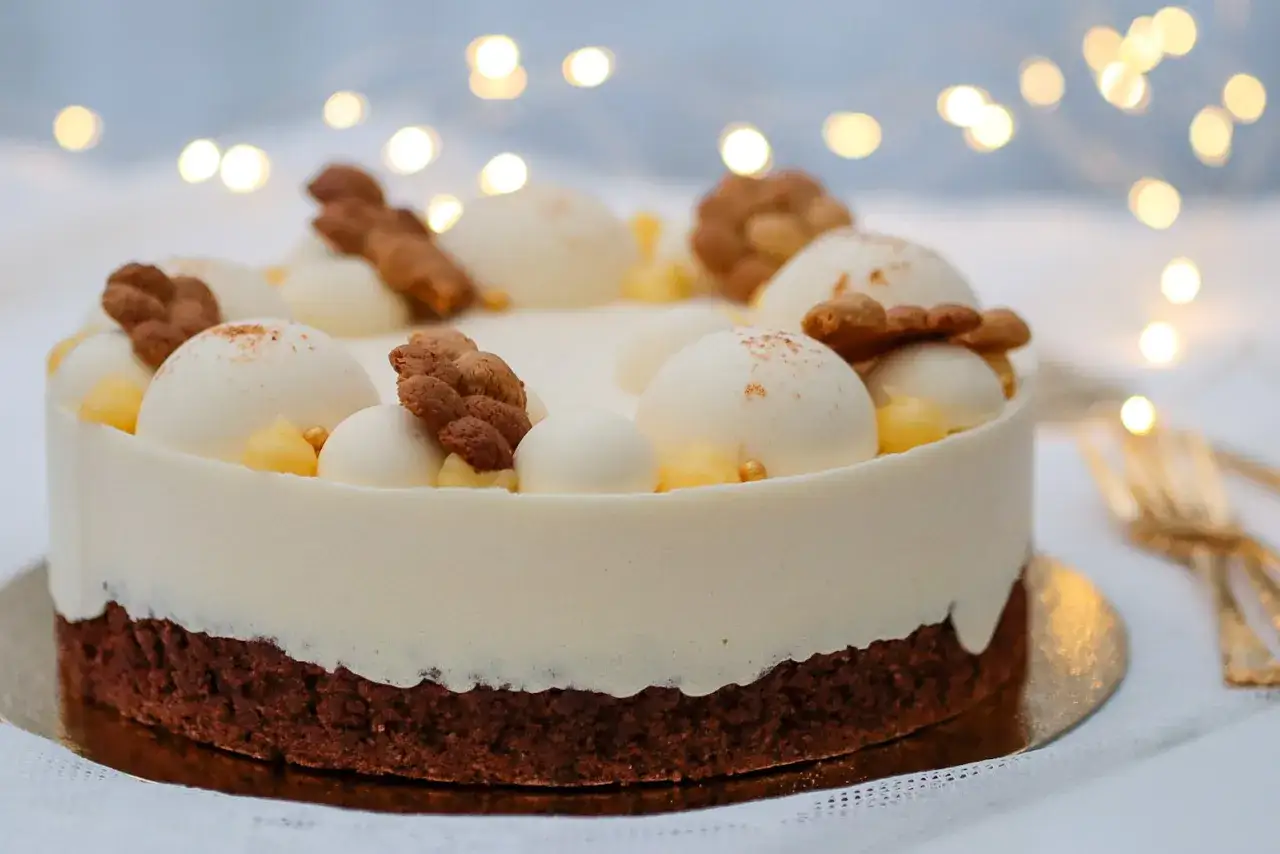 En elegant tårta med chokladbotten, täckt av vit mousse. Toppad med små vita bollar, krispiga kex och gul lemoncurd.
