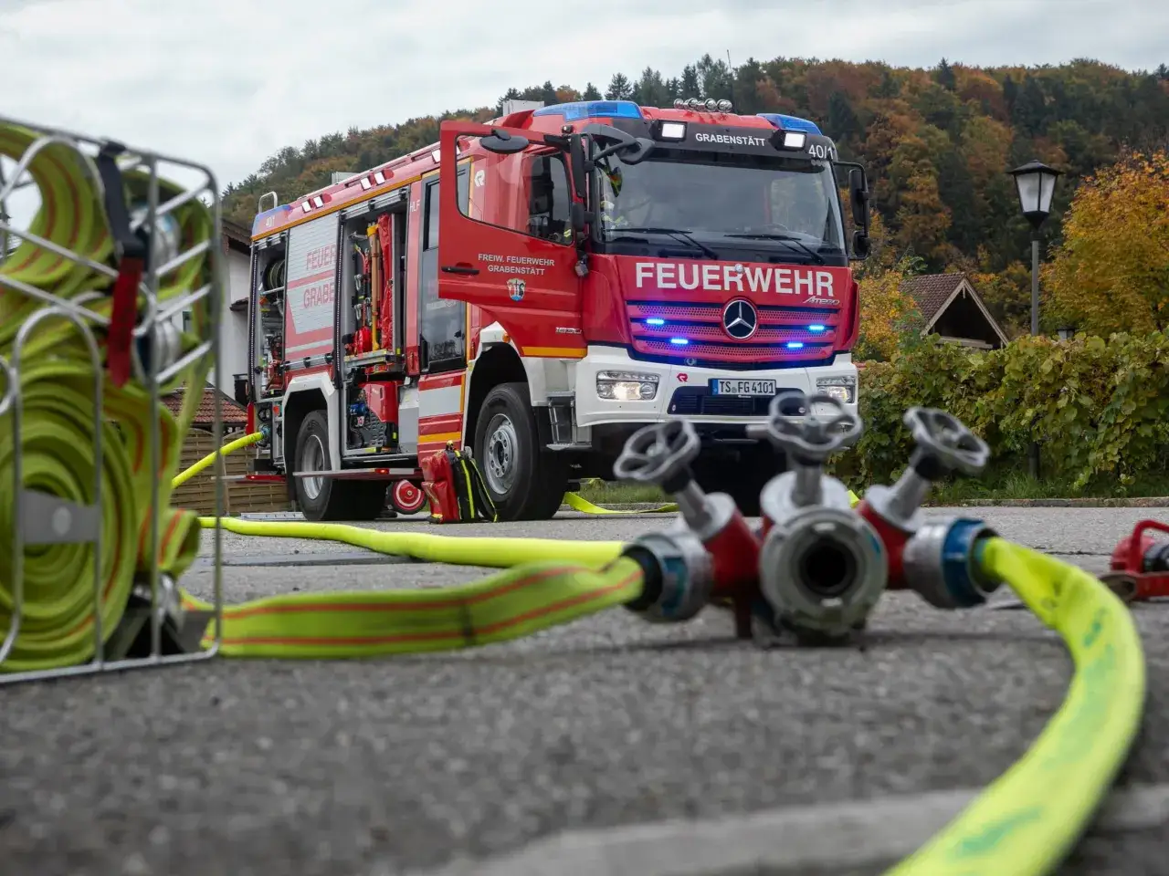 Rotes Löschfahrzeug der freiwilligen Feuerwehr Grabenstätt mit Schläuchen und Verteiler bereit für den Einsatz.