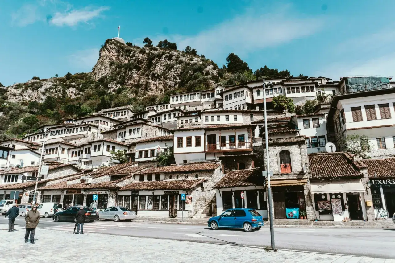 Malownicze domy na zboczu góry w Berat, Albania w październiku. Widok na zabytkowe miasto z charakterystycznymi białymi fasadami i kamiennymi dachami.