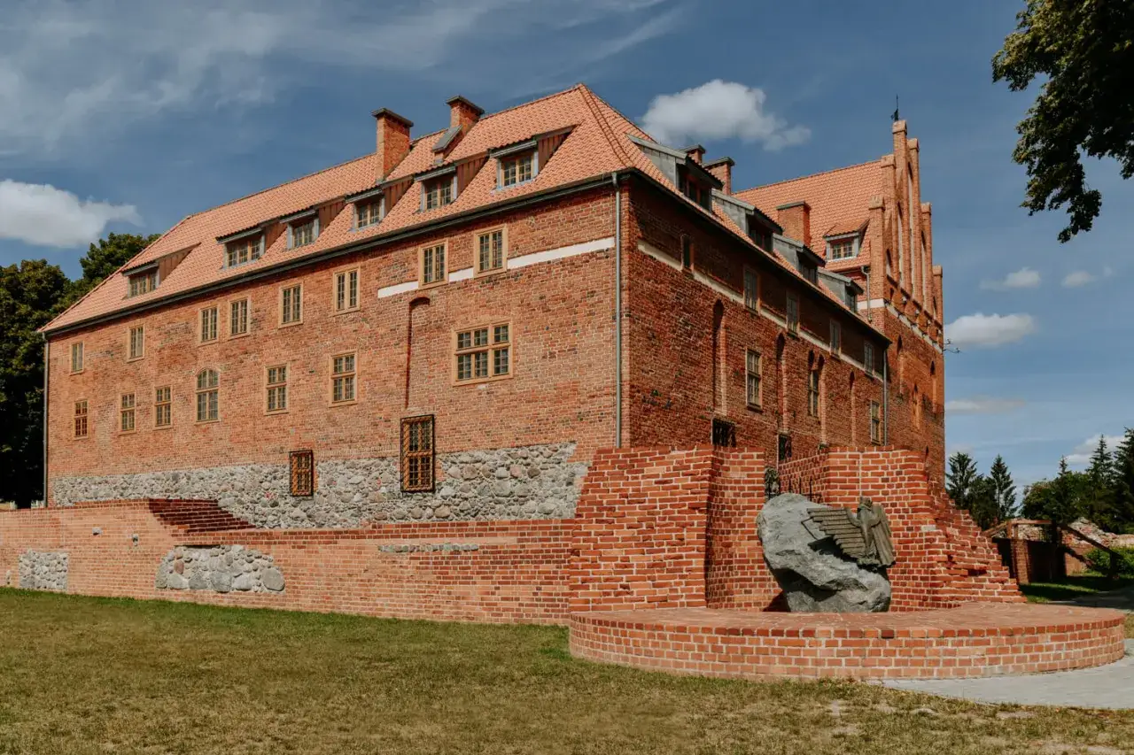 Zamek w Kętrzynie, jedna z głównych atrakcji miasta, prezentuje swoją ceglaną architekturę na tle błękitnego nieba.