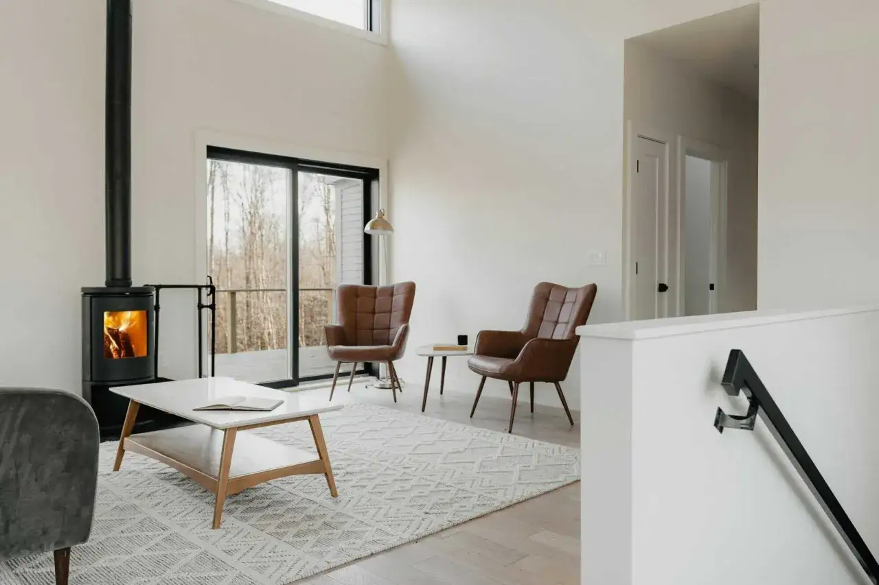 Gem&uuml;tliches Wohnzimmer mit brennendem Kaminofen, der einen leichten schornstein geruch in der wohnung verstr&ouml;mt. Zwei braune Ledersessel laden zum Entspannen ein.