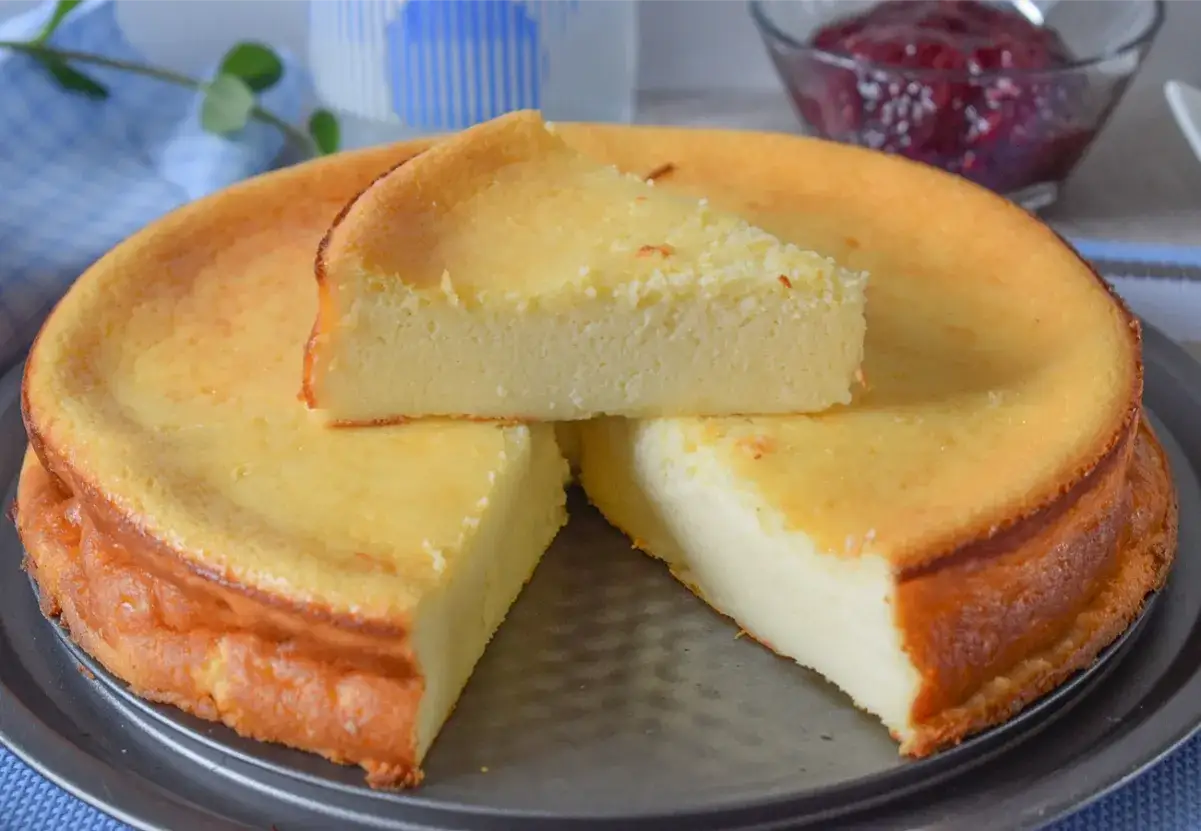 Deliciosa tarta de queso sin horno, con una rebanada servida encima. Suave y cremosa, perfecta para cualquier ocasión.