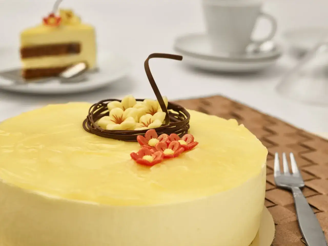 En vacker citronmousse till t&aring;rta, dekorerad med choklad och blommor. En bit av t&aring;rtan syns i bakgrunden.