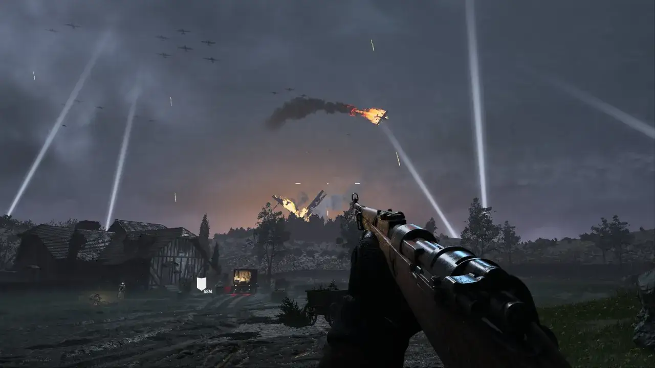 Widok z perspektywy gracza w Call of Duty Vanguard. W powietrzu widać samoloty i płonący wrak, a na ziemi dom i żołnierzy.