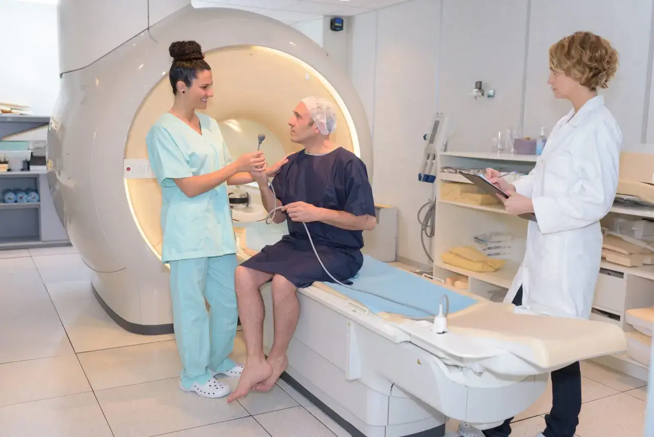 Pacjent przygotowuje się do badania rezonansem magnetycznym (mri). Lekarka wyjaśnia procedurę, a druga pielęgniarka notuje dane.