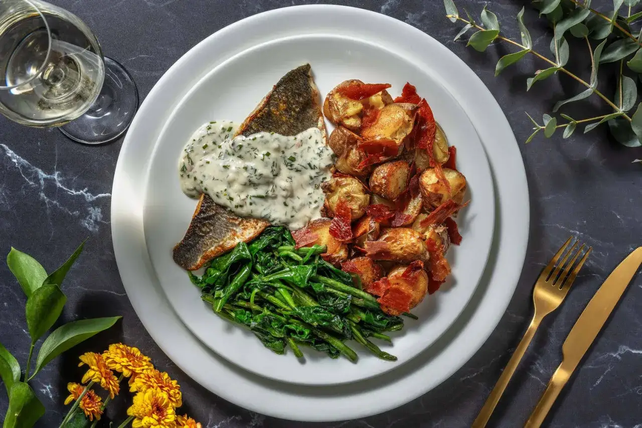 En tallrik med stekt fisk, krämig sås, gröna grönsaker och potatis med bacon. En balanserad måltid som ger bra med protein. Hur mycket protein per dag behöver du?