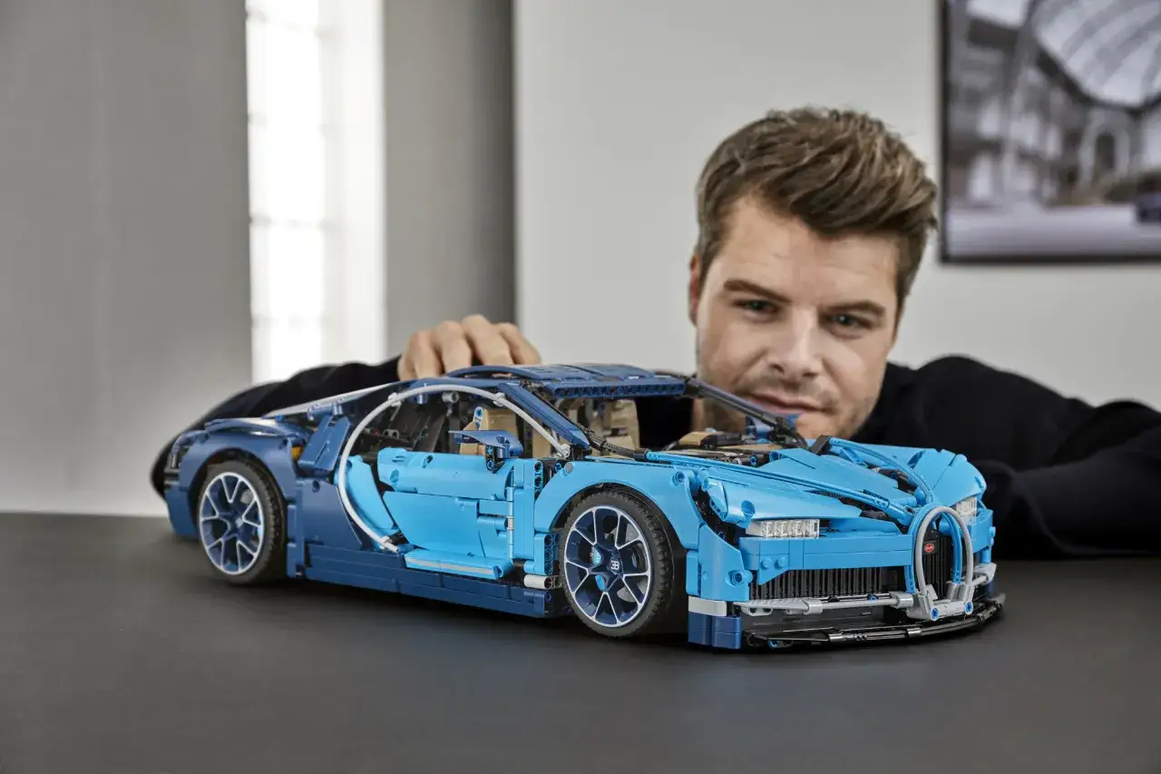 Mężczyzna z pasją składa niebieski model Bugatti z klocków LEGO. To pokazuje, dlaczego popularny raper zbiera klocki LEGO i ma na nie osobny pokój.