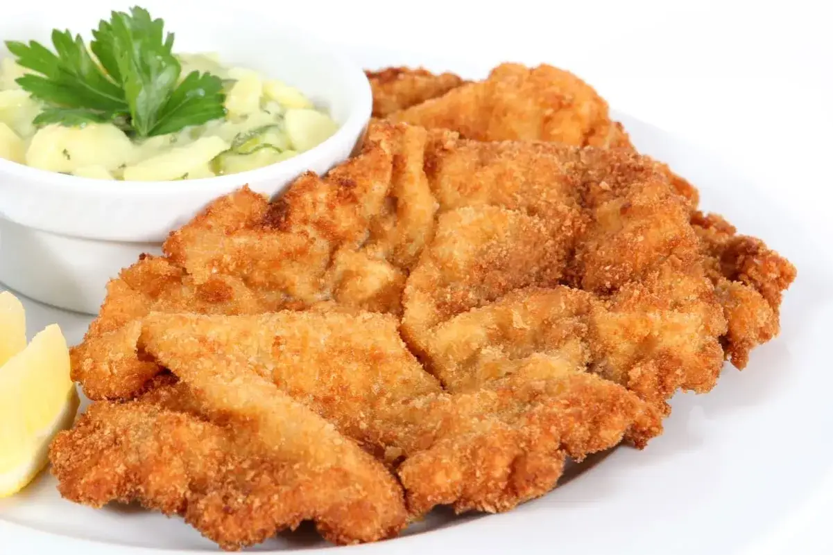 Knusprige Schnitzel mit Kartoffelsalat, perfekt paniert ohne Ei. Dazu ein Zitronenschnitz.