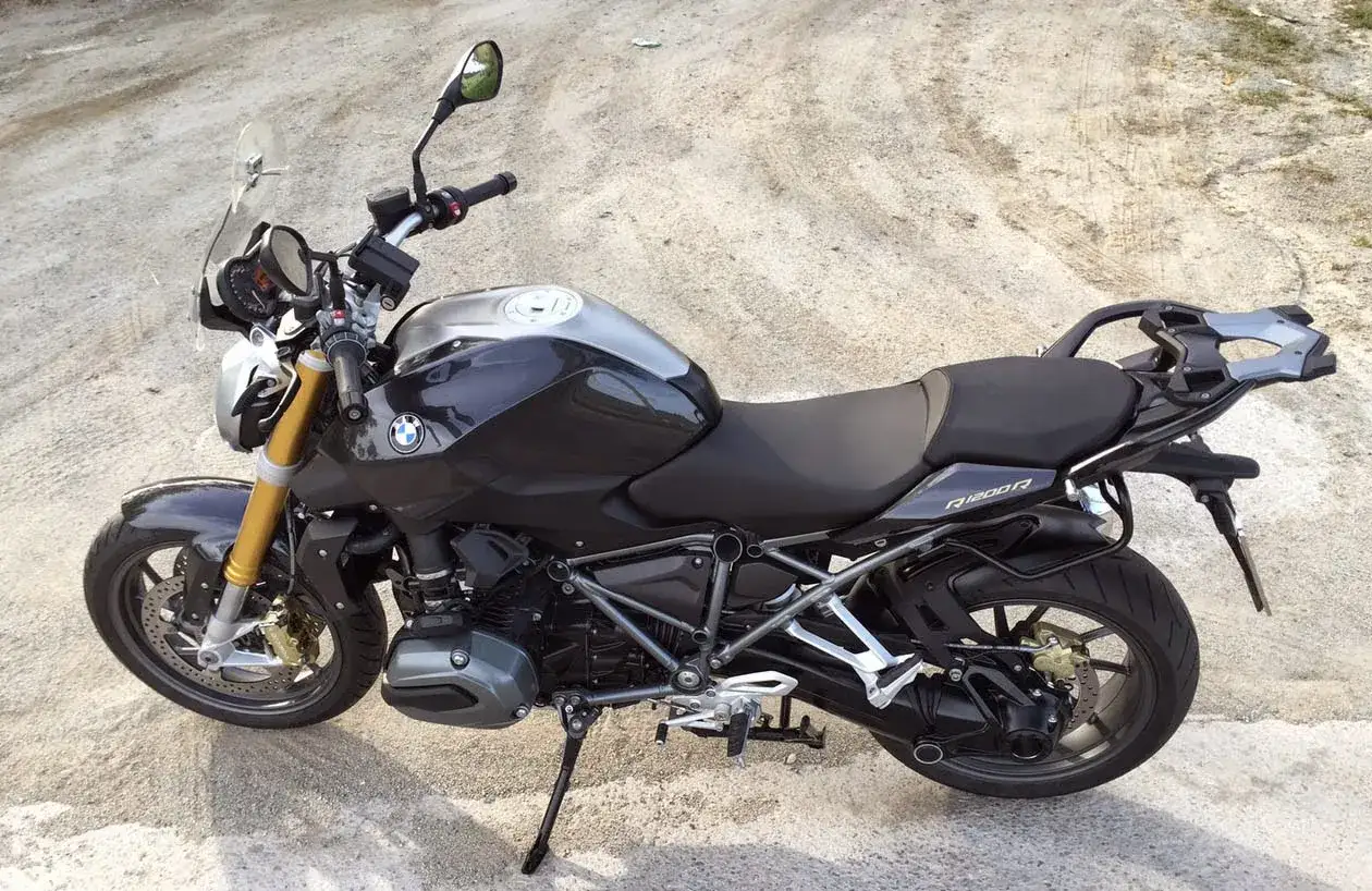 Detalle de la BMW R1200R, ideal para consultar su ficha t&eacute;cnica. Moto deportiva negra con detalles plateados y horquilla dorada.