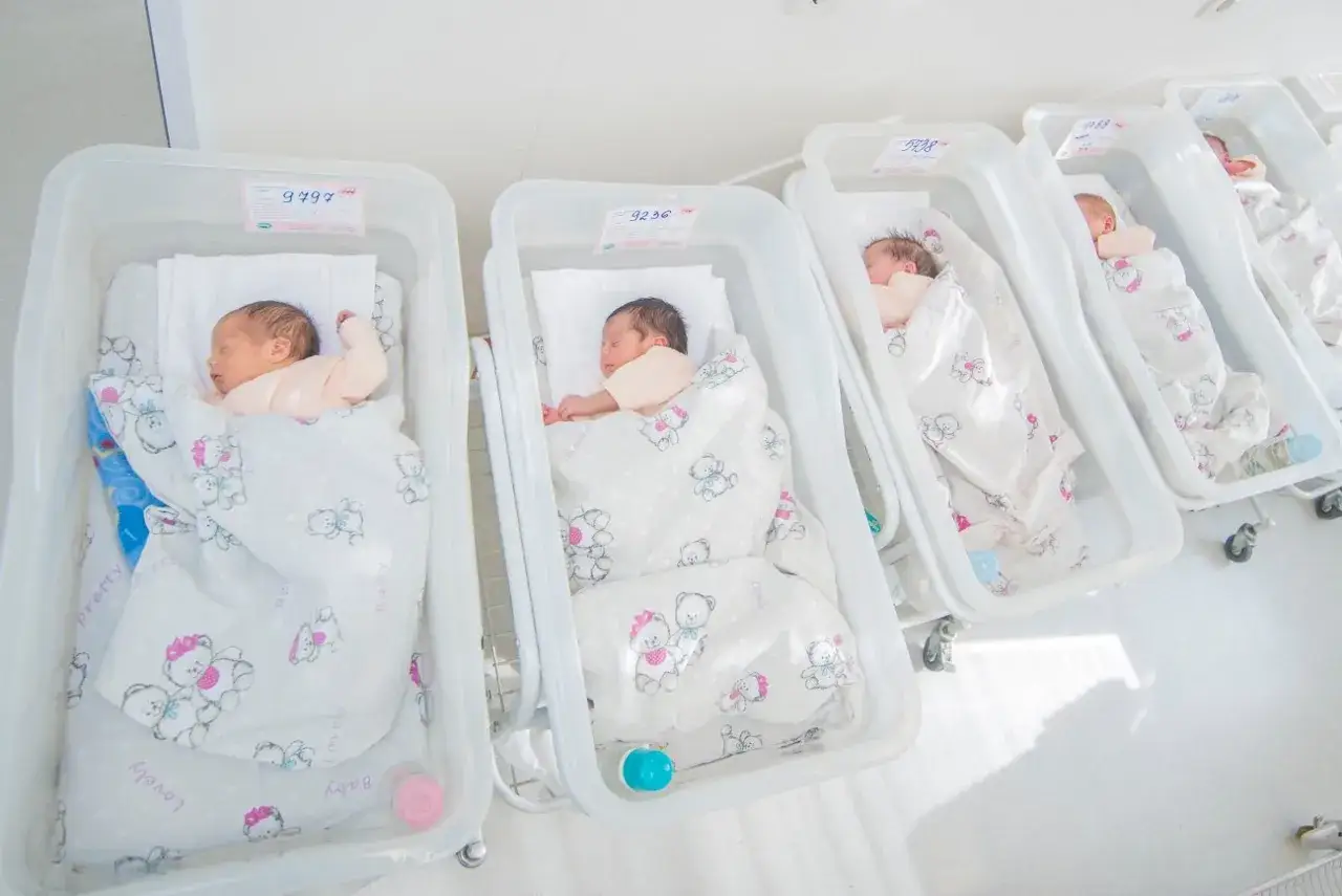 Szczęśliwe piecioraczki śpią w łóżeczkach, otulone kocykami z misiami.