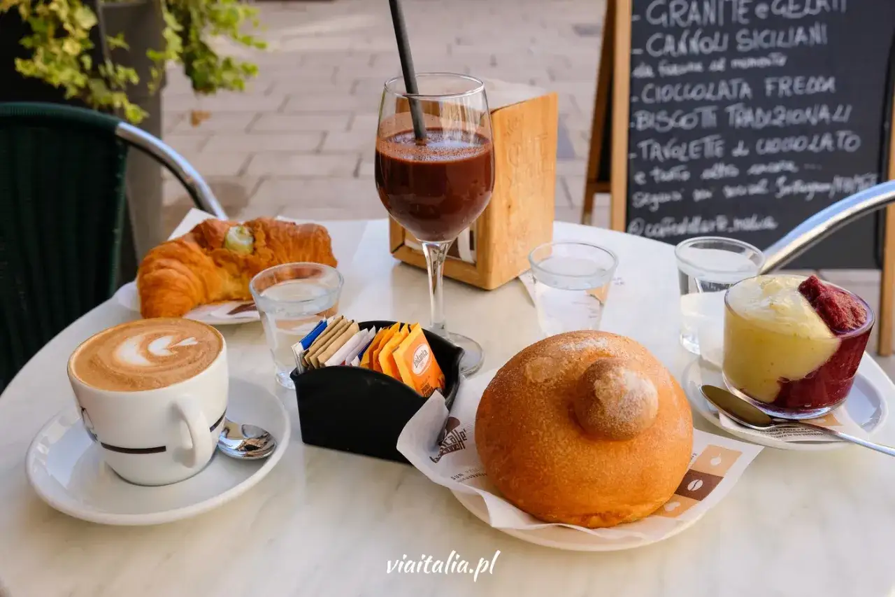Sycylia jedzenie: cappuccino, rogalik z pistacjami, brioche, czekolada i deser na stole kawiarnianym.