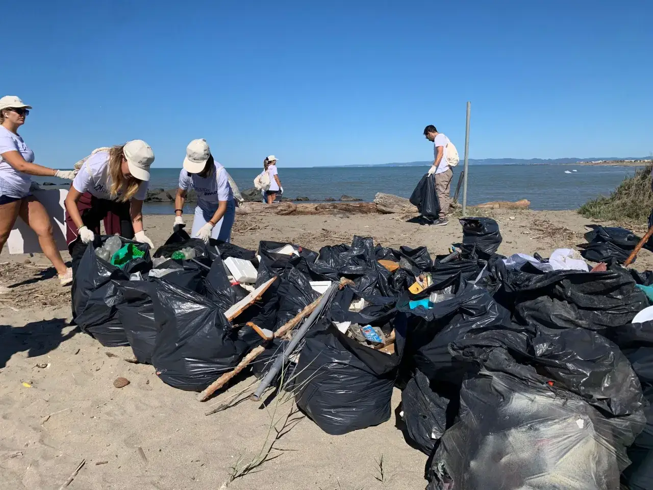Volontari raccolgono rifiuti sulla spiaggia, un esempio di come agire per **5 modi per salvare il mare**.