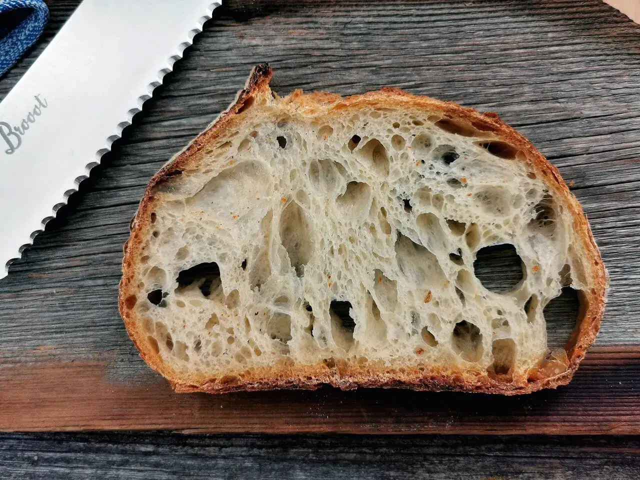 Schnitt eines Sauerteigbrotes mit gro&szlig;er Porung, das Ergebnis von guter Sauerteig Hefe. Daneben ein Brotmesser.