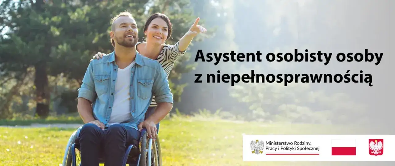Uśmiechnięta kobieta wspiera mężczyznę na wózku inwalidzkim, wskazując mu drogę. Asystent osoby niepełnosprawnej to wsparcie w codziennym życiu.