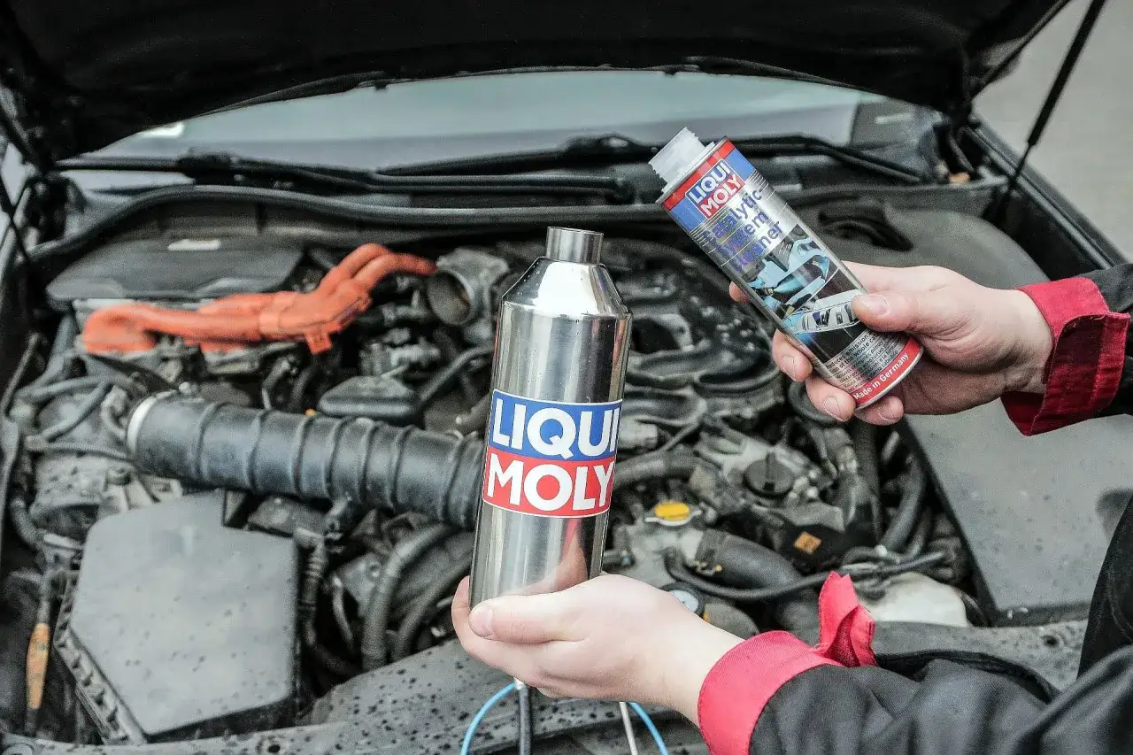 Czyszczenie katalizatora z użyciem preparatu Liqui Moly. Dłonie trzymają metalową puszkę i butelkę z płynem.