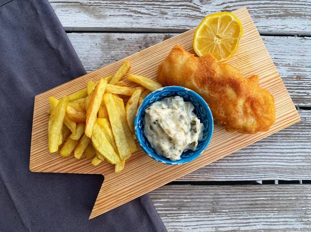 Idealny Fish and Chips przepis: chrupiące frytki, złocisty filet rybny w cieście, sos tatarski i plasterek cytryny.
