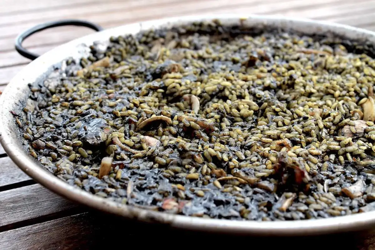 Un plato de arroz negro con mariscos, listo para ser disfrutado.