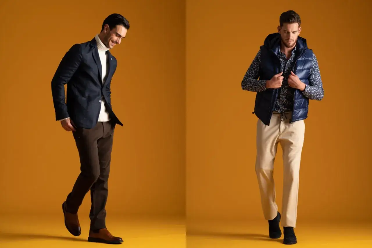 Uomo con giacca a quadri e dolcevita, pantaloni marroni e stivali. Accanto, un altro uomo con gilet blu, camicia fantasia e pantaloni beige. Il taglio pantaloni uomo è perfetto per entrambi.