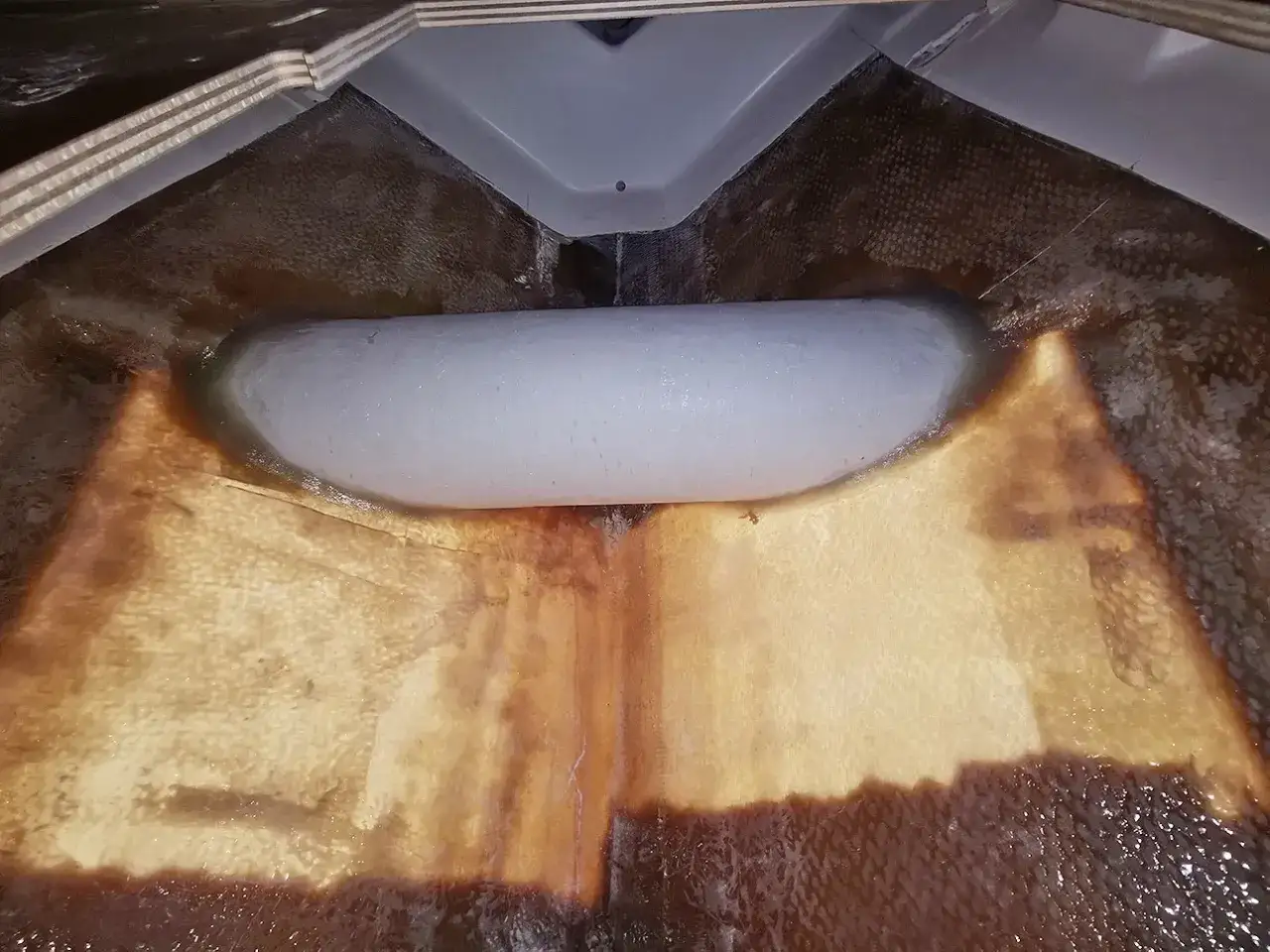 Le tube blanc d'un propulseur d'&eacute;trave est visible dans la coque d'un bateau, entour&eacute; de r&eacute;sine et de fibre de verre.