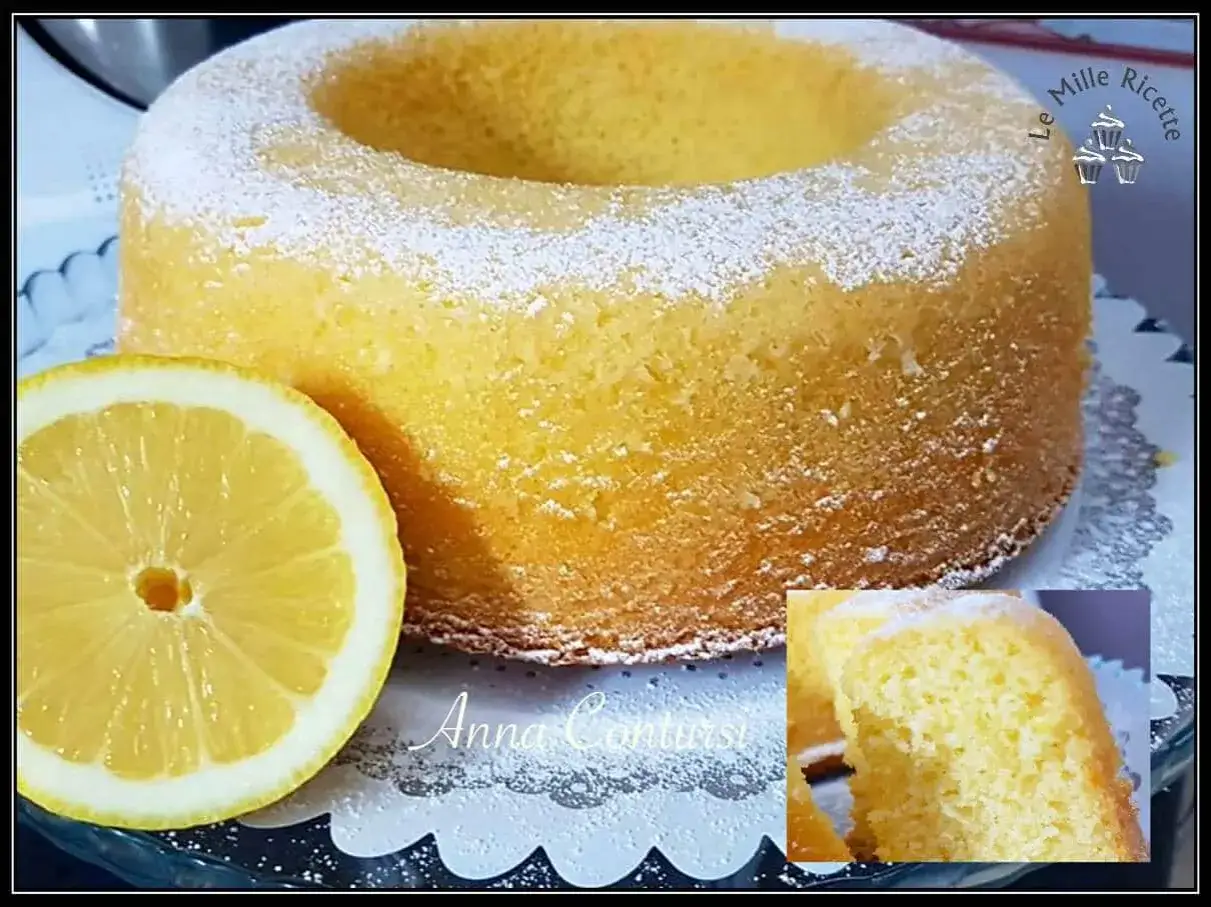 Ciambellone al limone soffice e profumato, spolverato di zucchero a velo, con una fetta di limone fresco accanto.