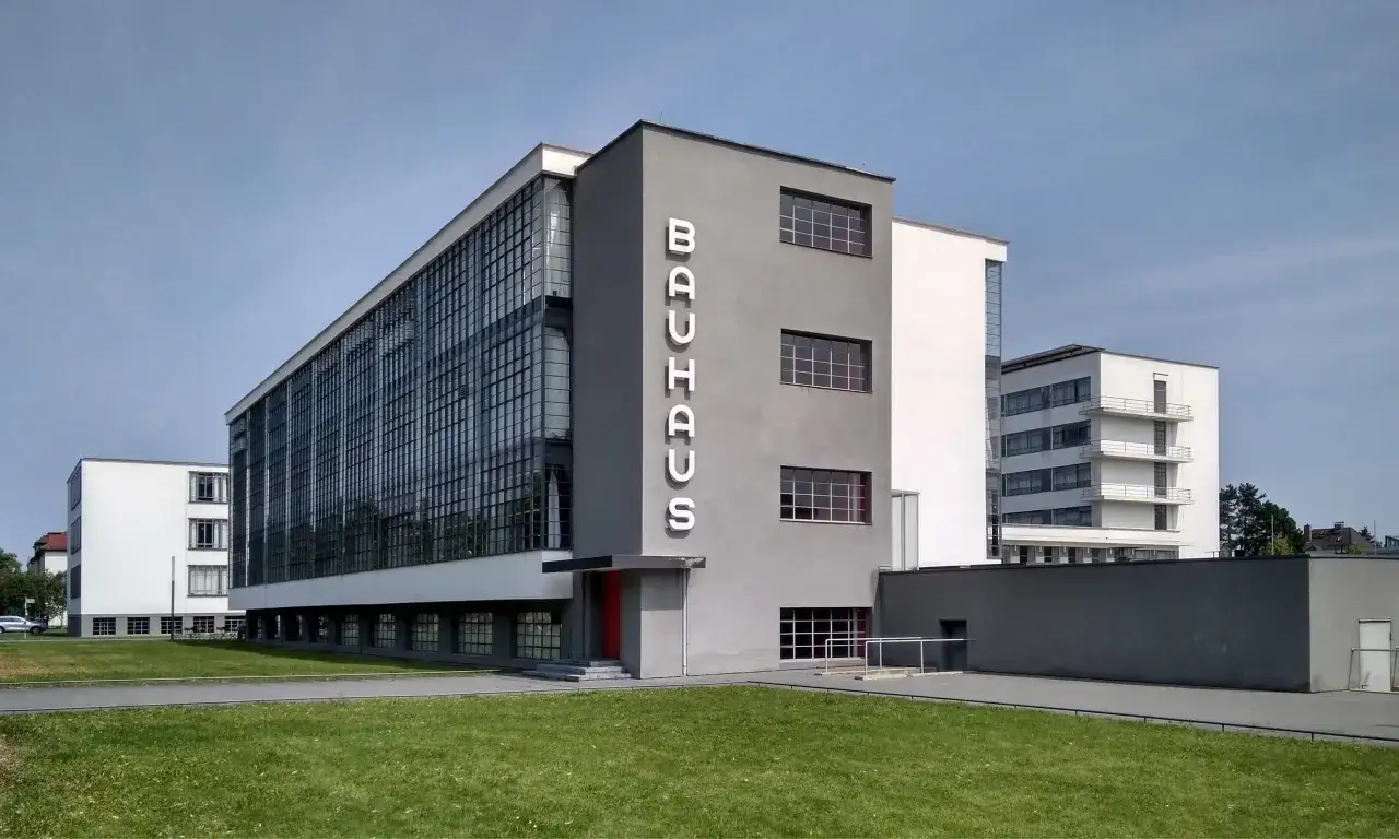 B&acirc;timent embl&eacute;matique du **Bauhaus mouvement**, avec sa fa&ccedil;ade vitr&eacute;e et son lettrage vertical. Un chef-d'&oelig;uvre d'architecture moderne.