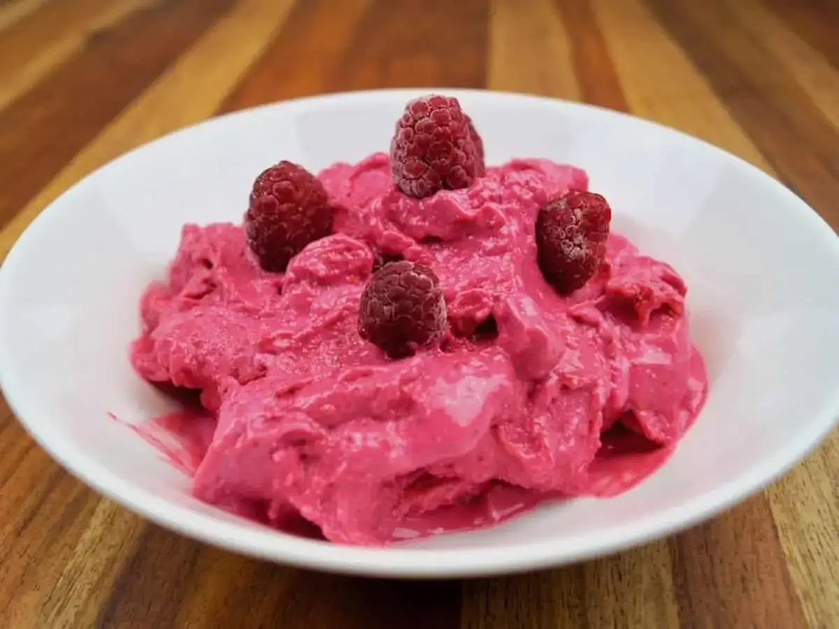 Himbeersorbet ohne Zucker, erfrischend und fruchtig, garniert mit frischen Himbeeren in einer weißen Schale.