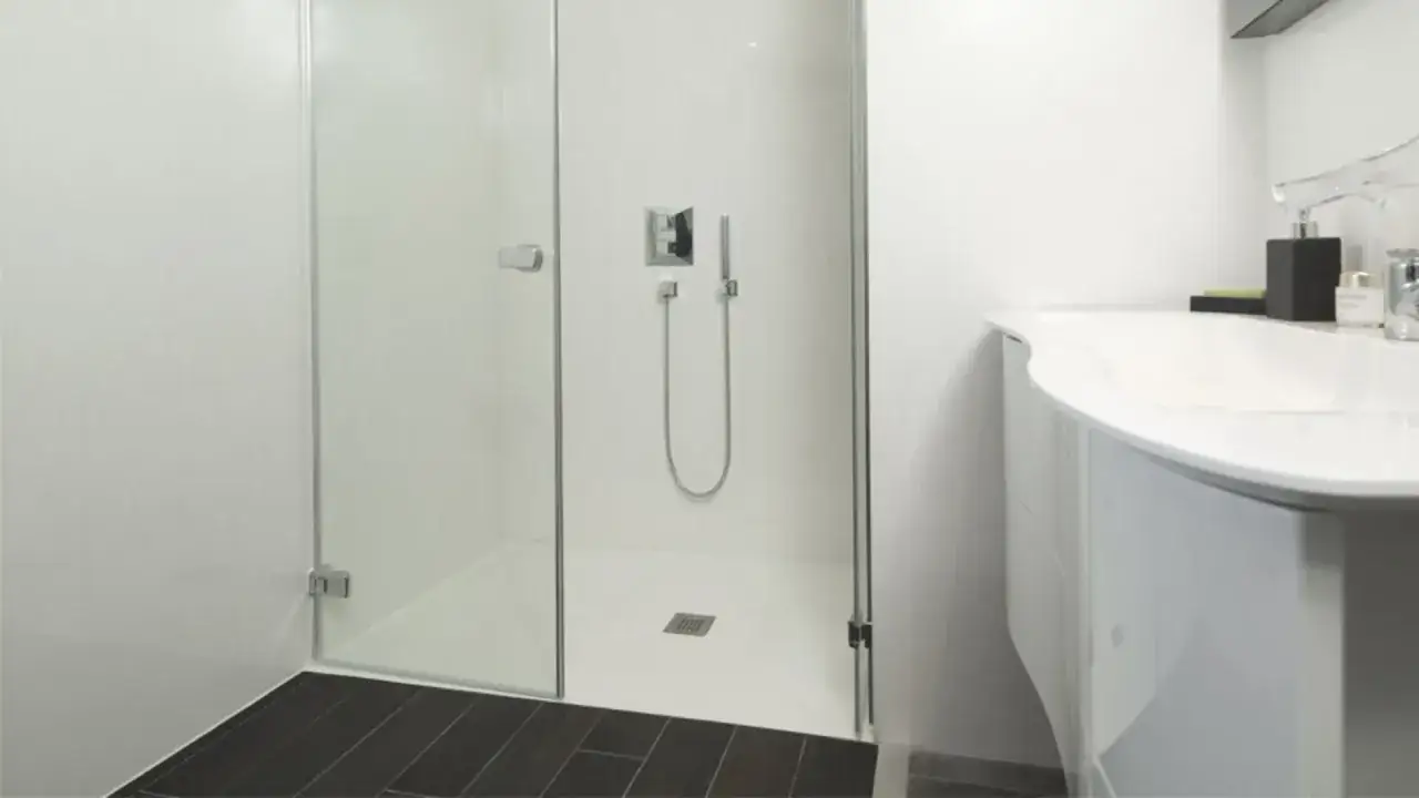 Salle de bain moderne avec douche &agrave; l'italienne et lavabo incurv&eacute;. Le sol de la douche est un ragr&eacute;age sur carrelage, offrant une surface lisse et uniforme.