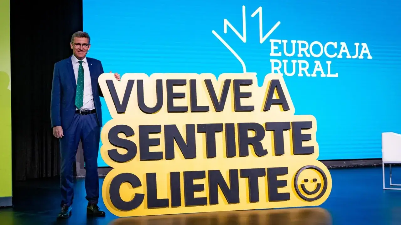 Hombre sonriente junto a un cartel de