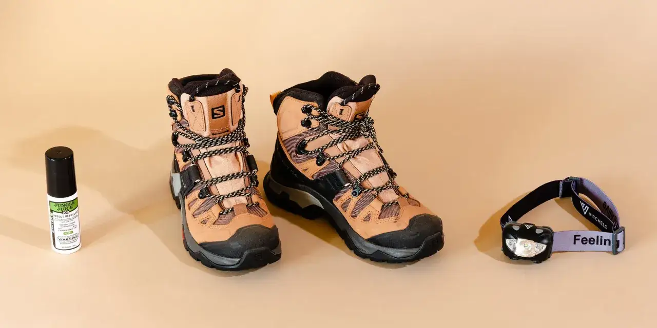 Paire de chaussures de marche longue distance, un spray anti-insectes et une lampe frontale. Prêt pour l'aventure !