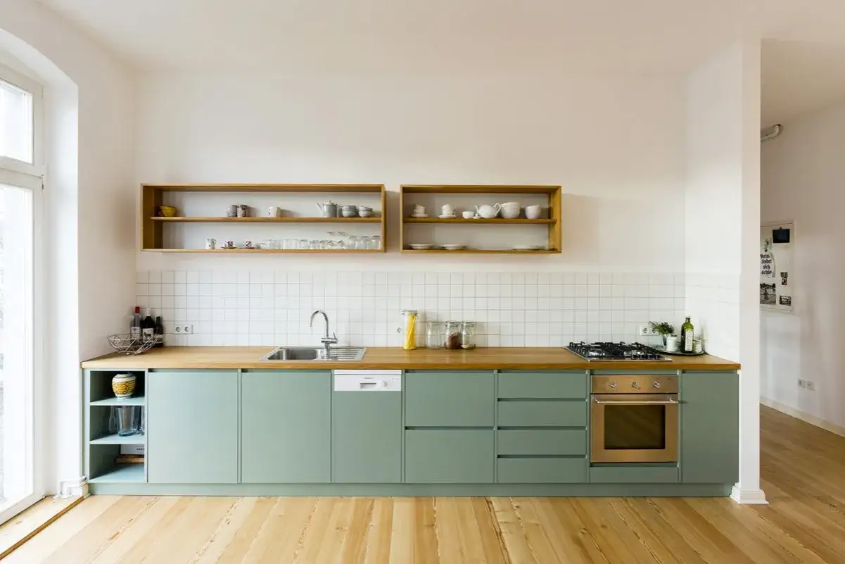 Cucina moderna con pensili verdi salvia e piano in legno. Ottimi abbinamenti colori cucine moderne per un ambiente luminoso e accogliente.