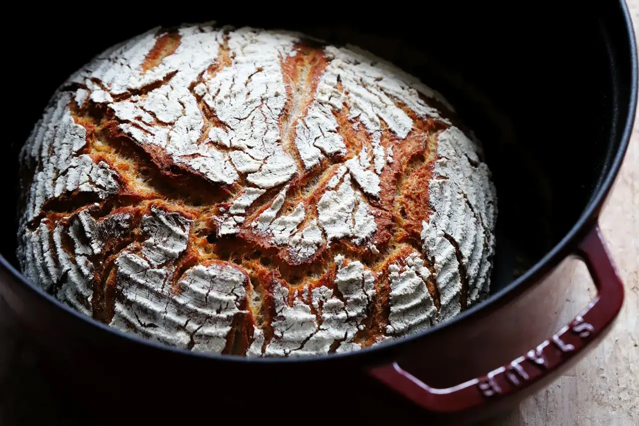Frisch gebackenes Brot mit knuspriger Kruste in einem gusseisernen Topf. Dieses energiesparend brot backen ist eine tolle Methode f&uuml;r perfekten Brotgenuss.